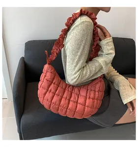 Detail van koraalrode gewatteerde tas met ruches aan de riem en zachte nylon stof