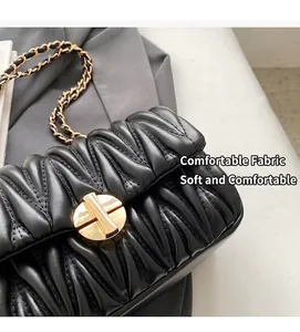 Detailansicht der Matelassé-Struktur aus schwarzem Leder und goldener Kette der Tasche