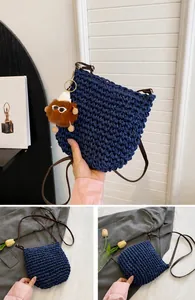 Detail van blauwe geweven strooien tas met leren riem en zachte pluche pompon-bedel