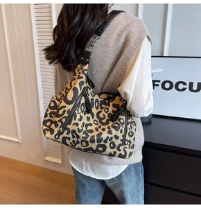 Detail view of large leopard print tote bag featuring black leather straps and zipper pockets