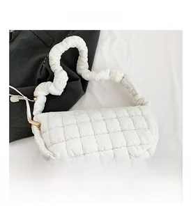 Detail of white quilted puffy shoulder bag with ruched strap and square texture