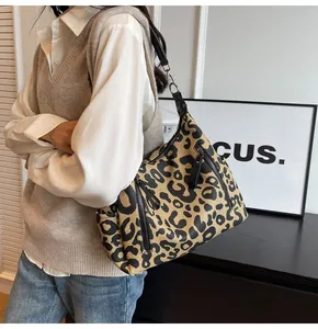 Close-up detail of leopard print tote bag with silver zippers and black leather strap