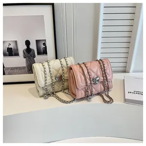 Détail de sacs matelassés beige et rose avec boucles en cœur et bandoulière chaîne