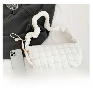 Detail of white quilted cloud bag featuring pleated straps and padded texture design