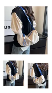 Detail of off-white crescent bag featuring a blue strap with bold FASHION lettering