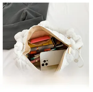 Top view showing large capacity of white quilted puffer bag with cosmetics and phone