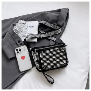 Vue détaillée du sac bandoulière noir à strass avec une large sangle en toile rayée