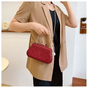 Detail of red rhinestone evening bag with gold metal handle on a model in a blazer