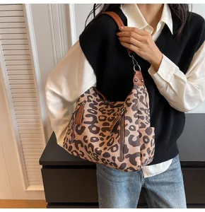 Detail of leopard print tote bag with brown leather straps and functional side zippers