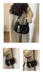 Detail of black crescent hobo bag featuring woven rope zipper and Fashion side label