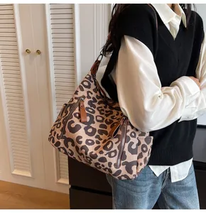 Detail of leopard print tote bag with brown leather handles and side zipper pocket