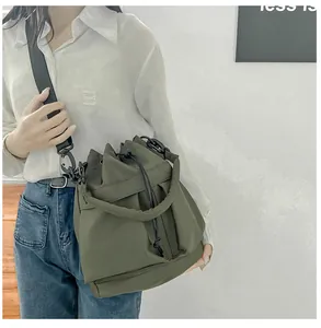 Detailweergave van legergroene nylon emmertas met verstelbare riemen op een model