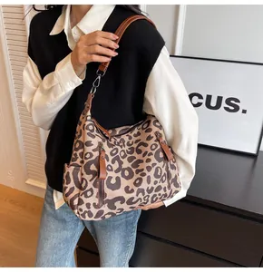 Detailed view of leopard print canvas hobo bag with brown leather straps and side pockets