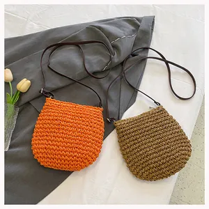Detail van geweven strooien crossbodytassen in oranje en kaki met leren riemen