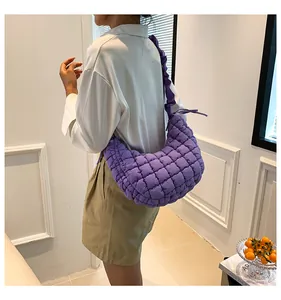 Detail van paarse gewatteerde schoudertas met geplooide riem en gewatteerde nylon textuur