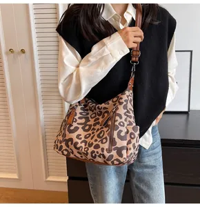Detailed shot of leopard print tote bag with brown leather straps and functional zippers
