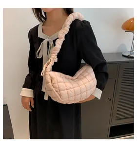Detail of light pink quilted crescent bag with a stylish pleated ruched strap handle