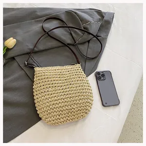Detail van geweven stro schoudertas met spiraaltextuur, lederen riem en bloemaccent