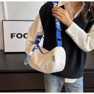 Detail of white crescent crossbody bag with adjustable blue branded fashion strap