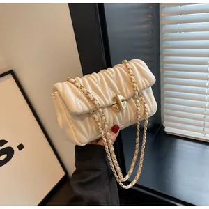 Details der weißen Rafftasche mit goldenem Drehverschluss und eleganter Faltenstruktur
