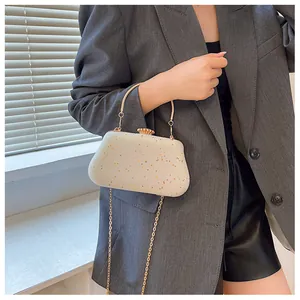Detail of glitter evening clutch bag with gold handle on grey blazer outfit