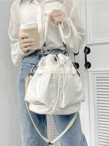 Minimalistische witte nylon bucket bag met trekkoord en verstelbare schouderband