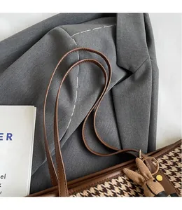 Detail of brown houndstooth tote bag with leather handles and cute rabbit charm accessory