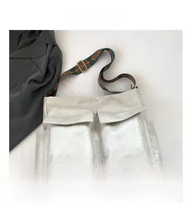 Detail of silver-grey tote bag showing dual front flap pockets and woven floral strap