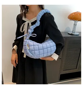Quilted light blue puffy bag featuring a pleated strap and decorative bow detailing