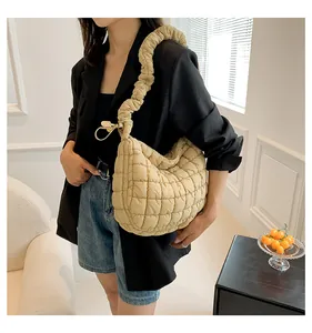 Detail van de gewatteerde beige schoudertas met geplooide band op een model gedragen