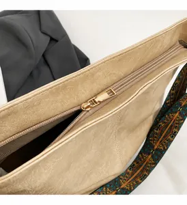 Detail of high-gloss gold zipper and colorful ethnic style strap on a beige tote bag