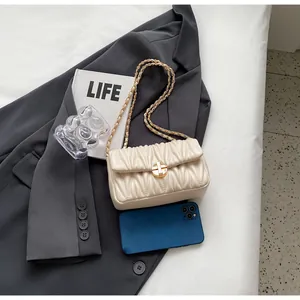 Detail der beige gesteppten Leder-Kettentasche mit goldfarbenem Verschluss auf Sakko