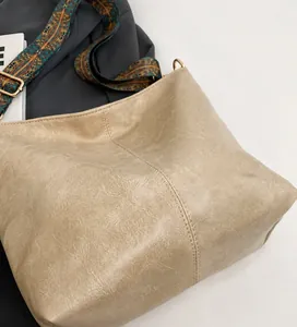 Close-up of beige tote bag with textured leather and colorful bohemian pattern strap