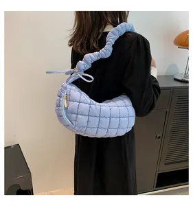 Close-up of light blue quilted crossbody bag with stylish ruched cloud shoulder strap