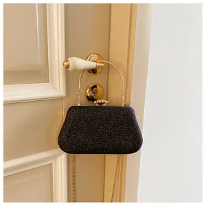 Close-up of glitter evening bag with gold metal handle hanging on an ivory door