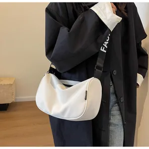 Detail of white crescent crossbody bag with wide black strap and fashion logo labels