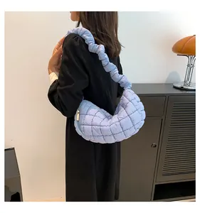 Close-up of sky blue quilted hobo bag with elastic scrunchie strap and gold zipper detail