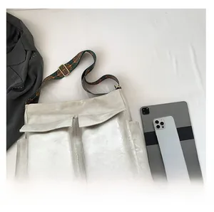 Detail of silver metallic tote bag featuring two front flap pockets and ethnic wide strap