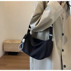 Detail of black crescent crossbody bag with white lettered wide strap and knot detail