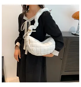Close-up of white quilted crescent bag with a distinctive padded ruched shoulder strap