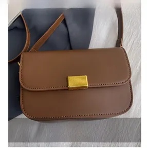 Close-up of brown leather bag with elegant golden rectangular metal hardware buckle