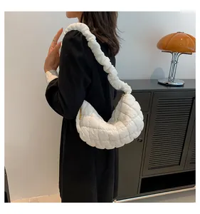 Detail of white quilted puffy shoulder bag featuring stylish ruched strap design