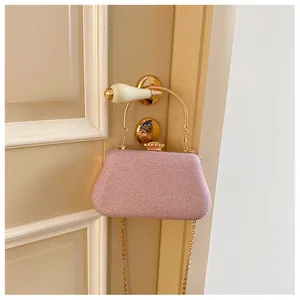 Detail of pink glitter evening bag with gold circular handle and detachable chain strap