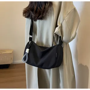 Detail of black nylon crescent bag with adjustable strap and fashion label on shoulder