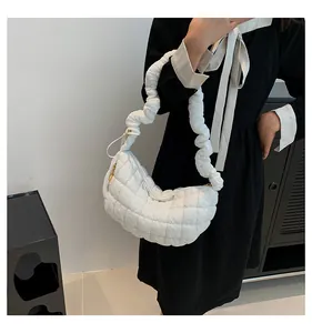 Detail of white quilted cloud crescent bag with ruched shoulder strap on female model