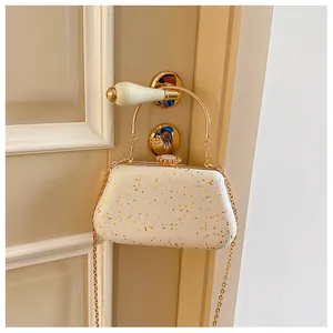 Close-up of white sequin evening bag with gold handle and star-shaped glitter accents