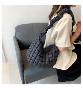 Detail van zwarte gewatteerde tas met puffy textuur en een geplooide schouderband