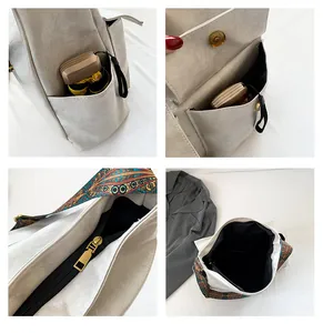 Detail view of large beige leather tote showing side pockets, zipper and wide boho strap