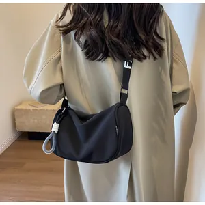 Close-up of matte black nylon crescent bag featuring white FASHION tag and rope zipper pull