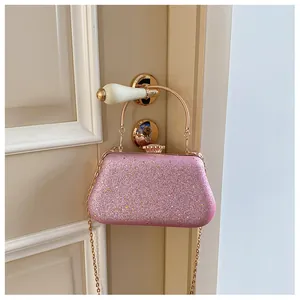 Close-up of pink glitter evening bag with metal handle and golden chain on a door